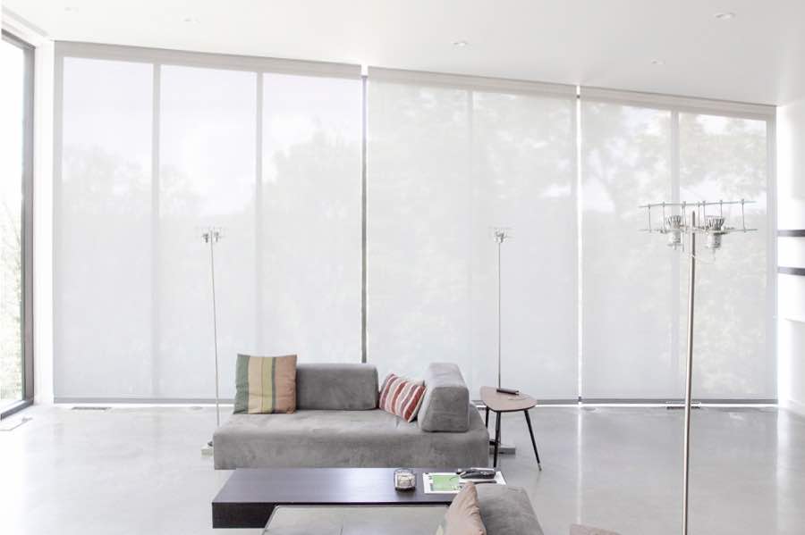 Motorized window shades make controlling natural light effortless in your Cleveland great room. White motorized shades on a wall of tall great room windows