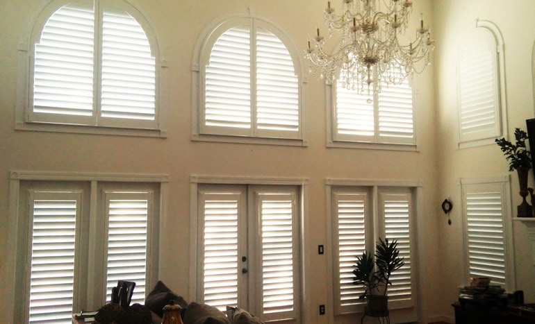 Great room in open concept Cleveland home with plantation shutters on arch windows.