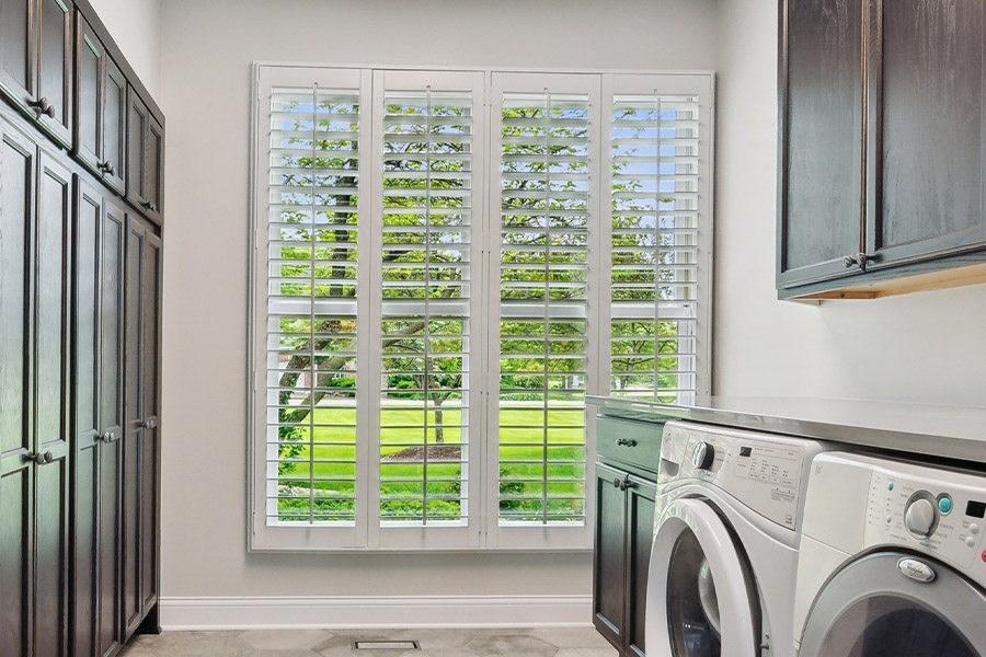 Find the perfect level of natural light for your Cleveland laundry room with interior shutters. White Polywood shutters letting light through a laundry room window