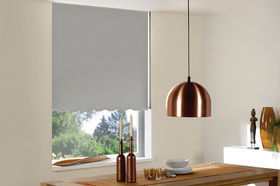 Spruce up your kitchen space with colorful and patterned window shades. Gray roller shades with scalloped edge in a small kitchen table area.