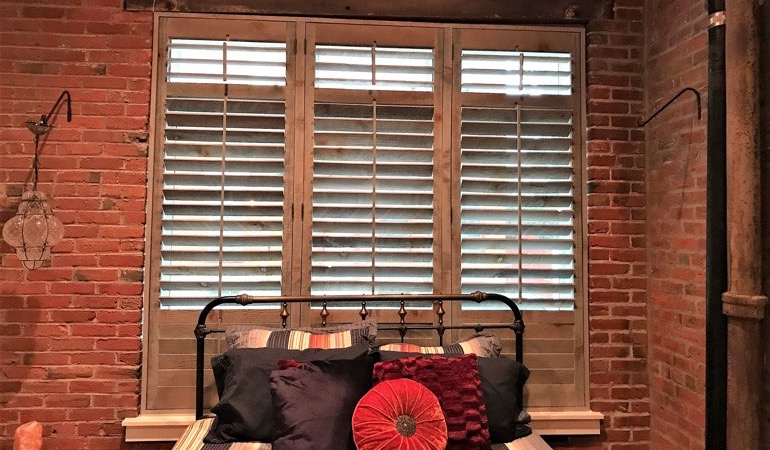 Reclaimed wood shutters provide a natural touch to your minimalist spaces. Reclaimed wood shutters near a brick wall.