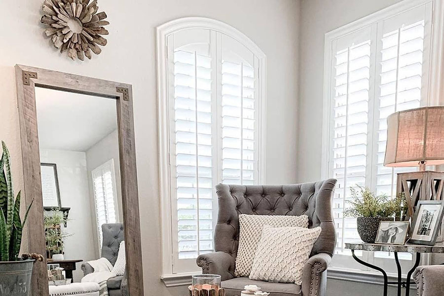 Create a cohesive look throughout your home with inspired interior shutters in all rooms. Tall white interior shutters in corner of sitting area