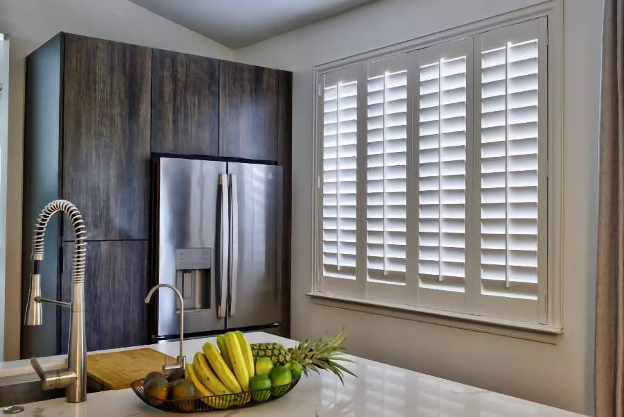 Homeowners use indoor window shutters in Cleveland when they want attractive and functional window treatments. Polywood shutters on a large kitchen window